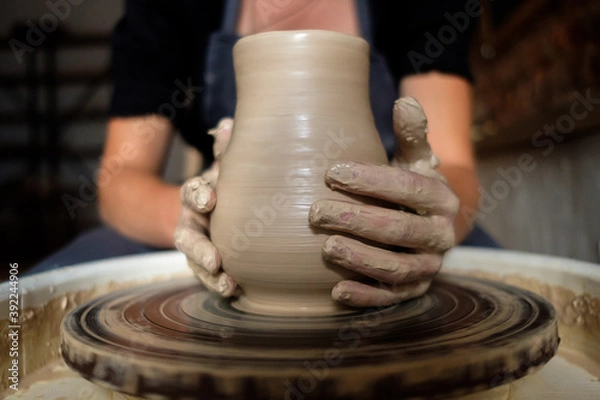 Fototapeta Female hands working with clay on a potter's wheel