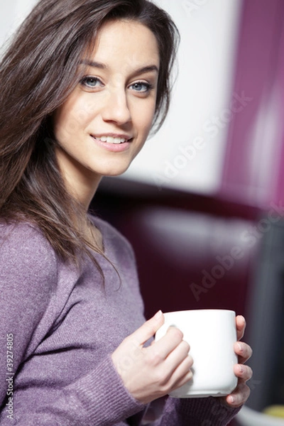 Fototapeta Beautiful young  woman having coffee while at the kitchen