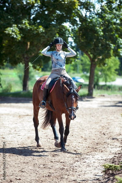 Fototapeta Young pretty girl at horse riding training process