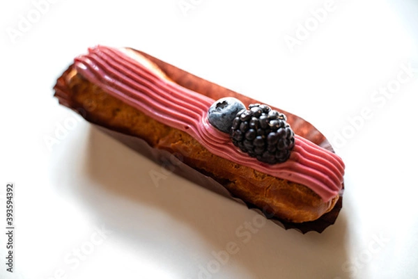 Fototapeta Crispy eclair with pink cream and blackberries and blueberries