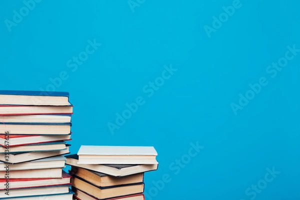 Fototapeta stacks of books for education in the college library on a blue background place for inscription