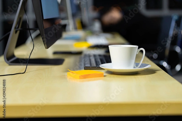 Fototapeta Business office desk with coffee cup and city light bokeh background.