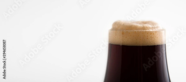 Fototapeta Part of frosty glass goblet of dark lager with many foam for client in pub