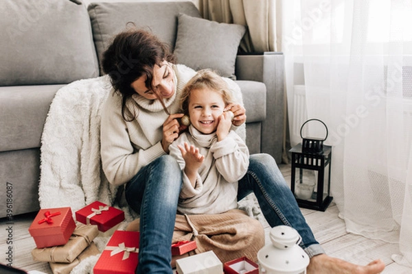 Fototapeta Young beautiful mother packing gifts having fun with her little daughter at home on Christmas and New Years Eve. corona virus, stay home, keep your distance