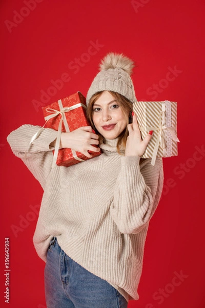 Fototapeta Dreaming winter girl holding Christmas gifts on background.