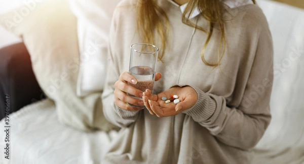 Fototapeta Close-up woman holding pills time to take medications, cure for headache. Medicine concept during self isolation and Coronavirus pandemic