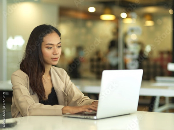 Fototapeta Portrait of businesswoman working with laptop in modern office room