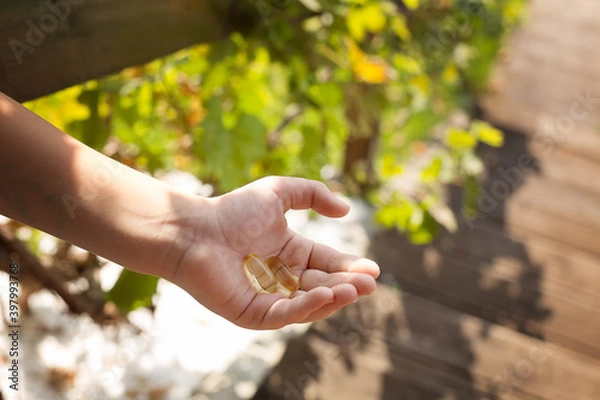 Fototapeta Vitamins in a child's hand in the sun.