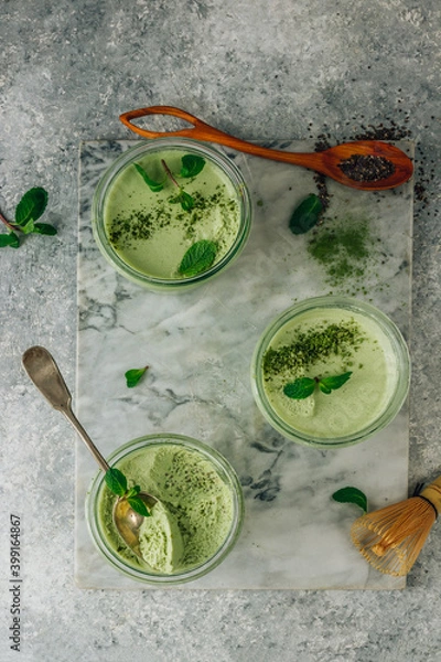 Fototapeta Raw vegan dessert. Matcha green tea chia seed pudding with fresh mint and coconut milk on a gray stone background.