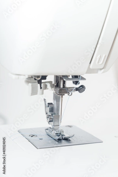 Fototapeta Vertical closeup of sewing machine needle against white background