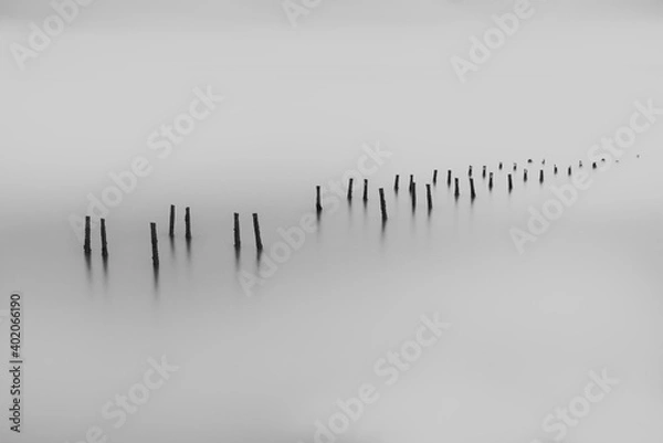 Fototapeta Minimalistic, fine art, Black and White landscape, old pier remains in a water surface