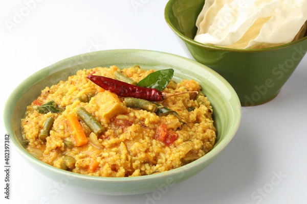 Fototapeta Sambar Rice - Tasty and popular south indian recipe served on banana leaf or  bowl with appalam or papad
