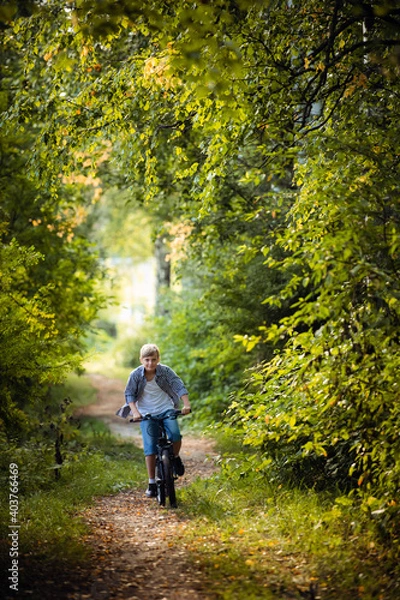 Fototapeta Preteen handsome boy with bicycle on the forest path