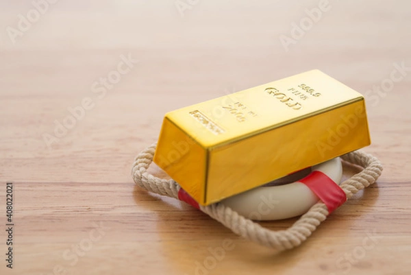 Fototapeta Gold bars or bullion on lifebuoy with wooden table background copy space. Investment insurance in commodity market trading price down concept. Insurance is risk managementin of investment.