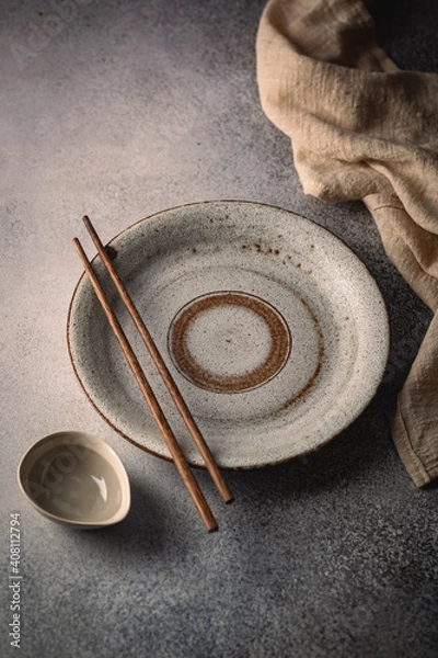 Fototapeta Empty plate with sushi chopsticks and gravy boat on gray table