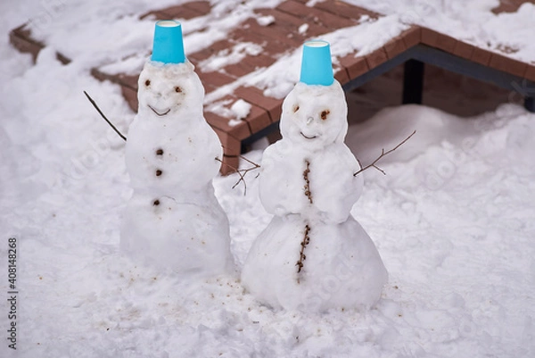 Fototapeta dancing snowmans with blue hats in the park. winter entertainment