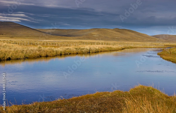 Fototapeta Pampas landscape with river and rolling hills on Tierra del Fuego in autumn