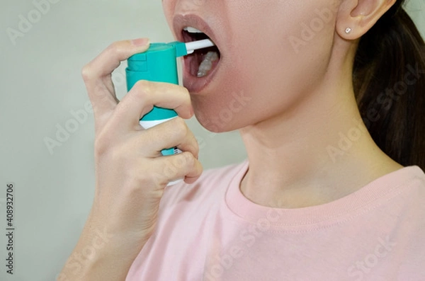 Fototapeta girl treats her throat with a spray in her mouth