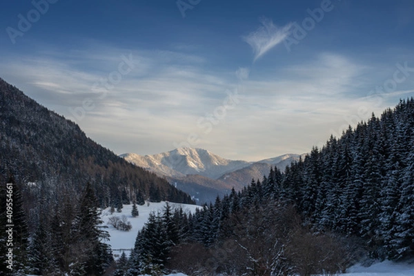 Fototapeta Snow covered hilly landscape in the evening.Mountain peaks in the background.