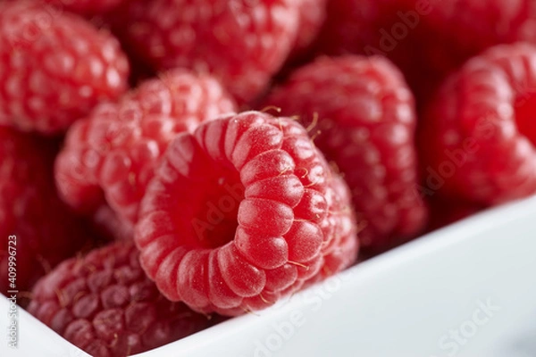 Fototapeta Ripe raspberry in small white bowl on white a wooden background.