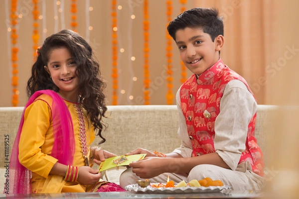 Fototapeta young brother giving money envelope to his sister	