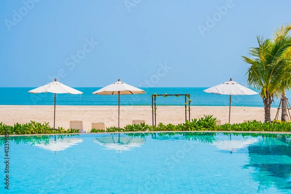 Fototapeta Umbrella and chair around outdoor swimming pool in hotel resort