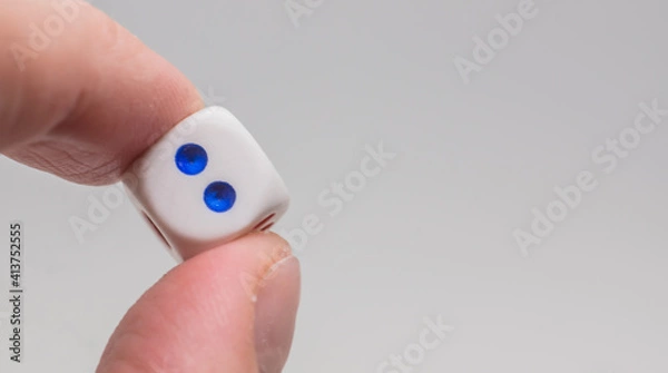 Fototapeta One dice with number two in hand. White dice on white background. Concept of luck, chance and leisure fun.