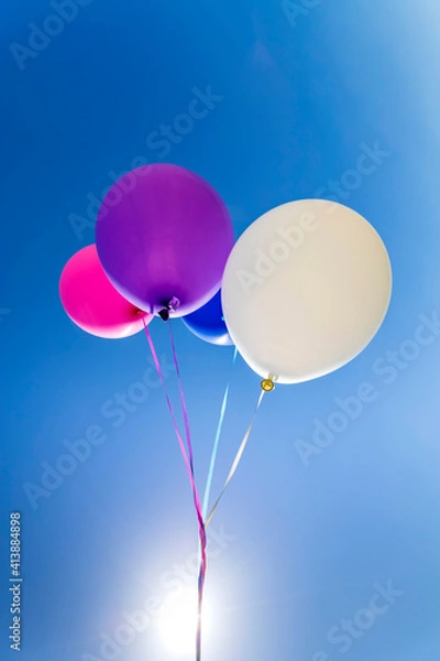 Fototapeta Multicolored inflatable balloons filled with helium against the blue sky.