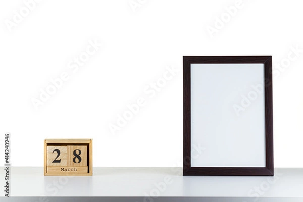 Fototapeta Wooden calendar 28 march with frame for photo on white table and background