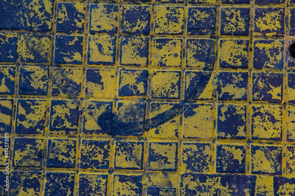 Fototapeta The texture of a manhole cover drenched in yellow paint.