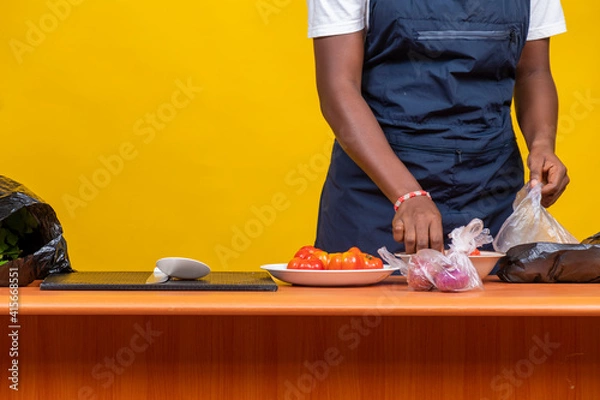 Fototapeta black chef sorting out cooking ingredients. female african chef, hands only, preparing ingredients for cooking