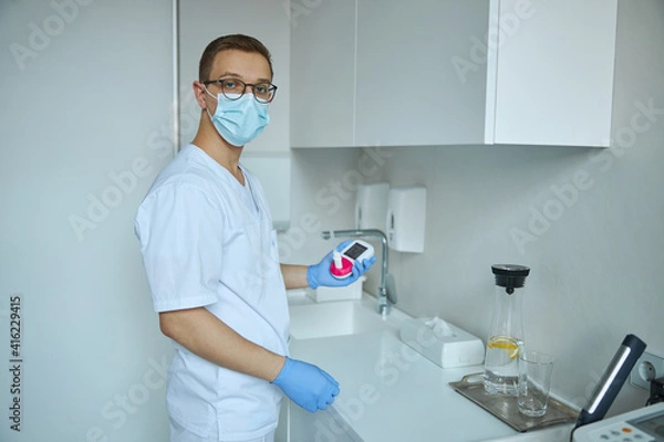 Fototapeta Pulmonologist with a handheld digital spirometer standing at his office