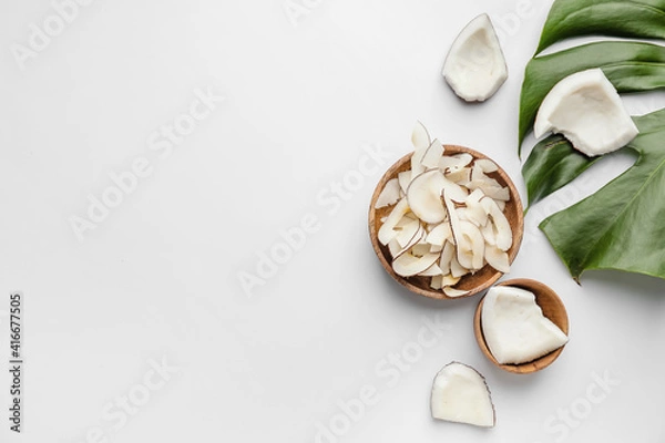 Fototapeta Bowl with tasty coconut chips on light background