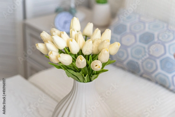 Fototapeta Tulips flowers in white vase on the living room coffee table. Composing bouquet. Still life