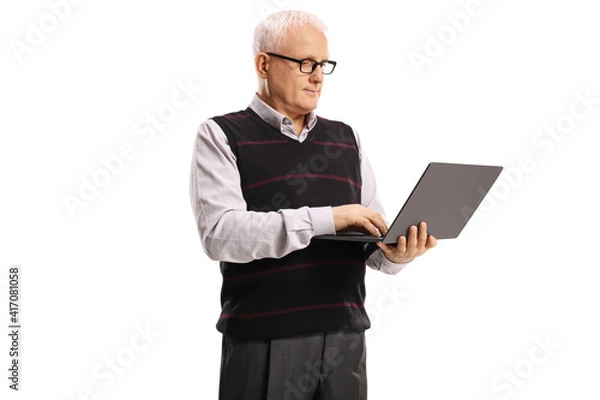 Fototapeta Mature man standing and working on a laptop computer