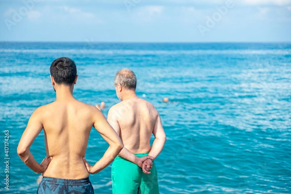 Fototapeta Guy and his father looking at the sea