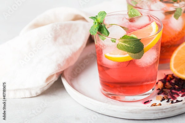 Fototapeta red tea karkade sparkling cold in glasses with mint, ice and lemon