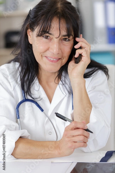 Fototapeta mature smiling female doctor on the phone