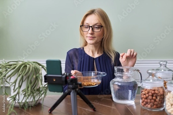 Fototapeta Activation of vitamins and minerals in nuts. Woman nutritionist soaking nuts in water