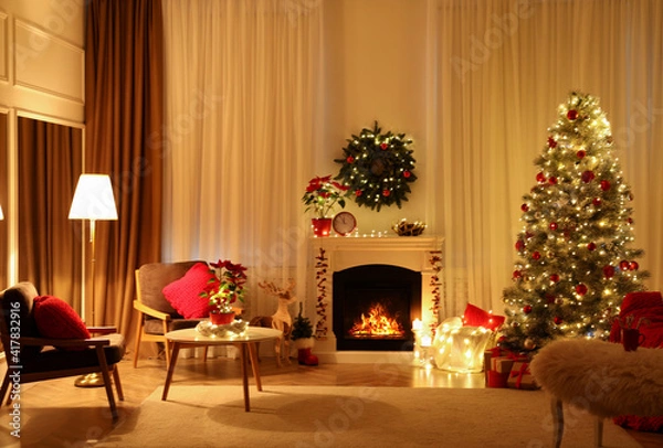 Fototapeta Beautiful living room interior with burning fireplace and Christmas tree in evening