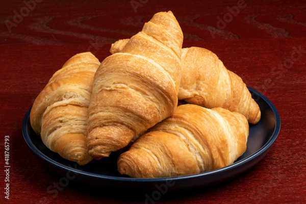 Fototapeta A pile of fresh baked butter croissants on a blue plate
