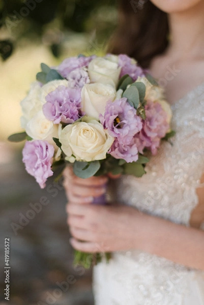 Fototapeta hand of the bride in a white dress and a wedding bouquet close-up