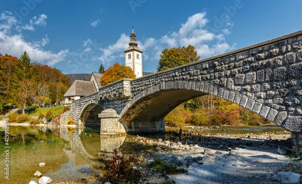 Fototapeta Amazing Sunny nature landscape with fabulous mountain lake in Slovenia. beautiful lake Bohinj with perfect sky at summer. view on calm lake with azure water, church and stone bridge on background