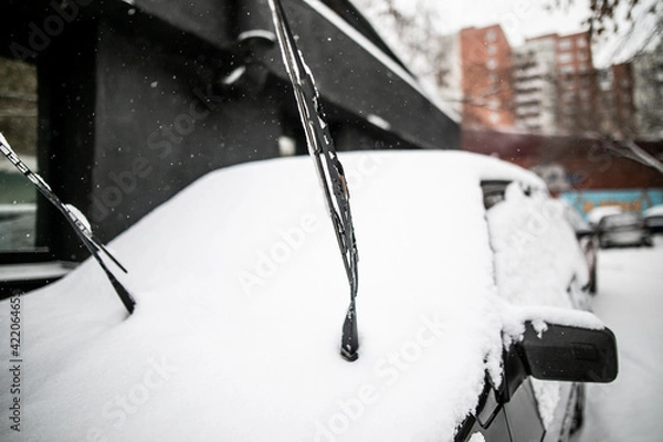 Fototapeta the raised wiper on the car is covered with ice and snow. Ice covered car window close up.