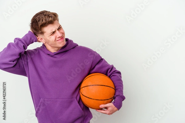 Fototapeta Young caucasian man playing basketball isolated background touching back of head, thinking and making a choice.