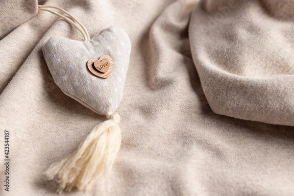 Fototapeta Mothers day background with soft beige heart on fabric backdrop. Symbol of love. soft focus. close-up