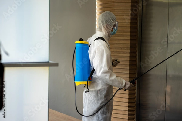 Fototapeta Asian healthcare medical workers wearing PPE protective suit disinfecting to building in new normal 