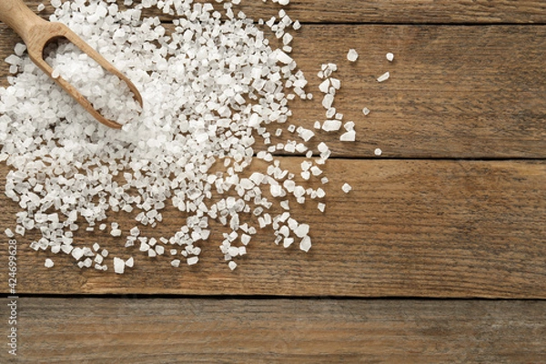 Fototapeta Natural sea salt and scoop on wooden table, flat lay. Space for text