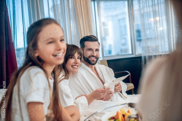 Fototapeta Parents and kids having breakfast and looking contented