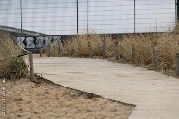 Fototapeta Beach with a wooden path as a closeup on a cold day